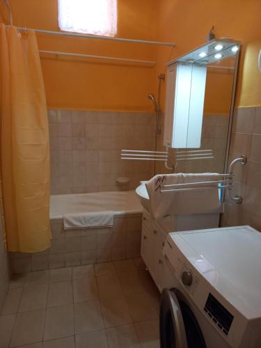 La salle de bains est pourvue d'une baignoire, d'un lavabo et d'un miroir. dans l'établissement Szent István Apartman, à Makó