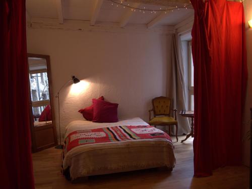 1 dormitorio con 1 cama con cortinas rojas y ventana en Chaleureuse maison avec Jacuzzi en Le Mas-dʼAzil