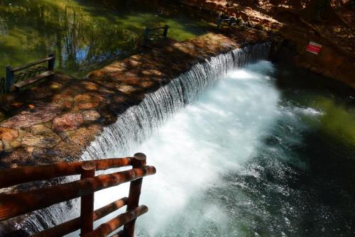 a waterfall with a wooden fence next to a river at Prime Hotel Águas da Serra in Rio Quente