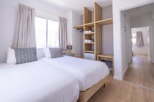 a white bedroom with a large bed and a window at KSQUARED in Protaras