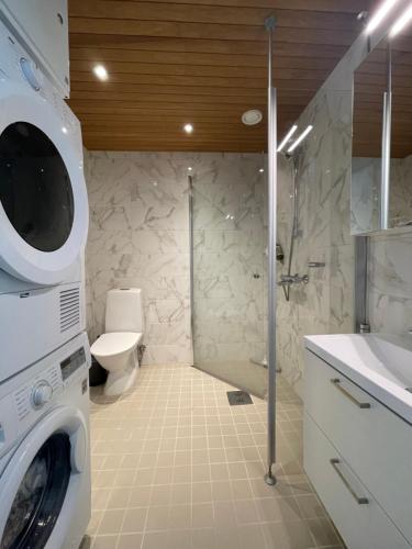 uma casa de banho com uma máquina de lavar roupa e um lavatório em The Seaside Apartment Turku em Turku