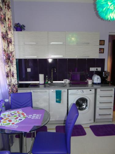 a kitchen with purple chairs and a table and a washing machine at Orange Flower Apartments 1 in Sofia