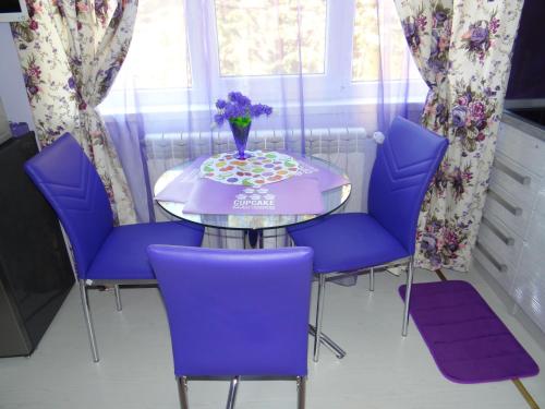 a table with purple chairs and a vase of flowers on it at Orange Flower Apartments 1 in Sofia