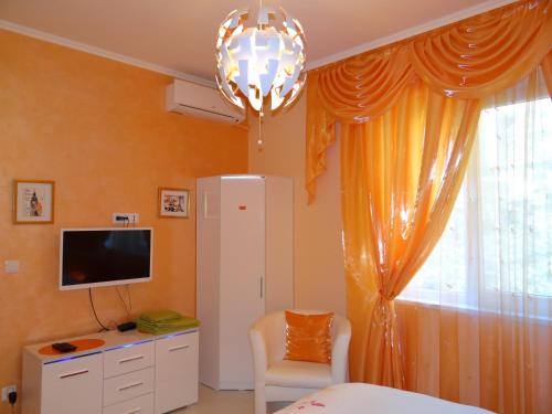 1 dormitorio con paredes de color naranja, TV y lámpara de araña en Orange Flower Apartments 1, en Sofía