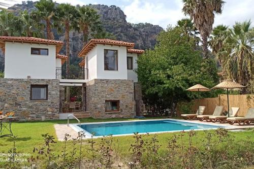 a villa with a swimming pool in front of a house at Villa Merry - Dalyan Stonehouse with Palmtrees, 50m to River in Ortaca