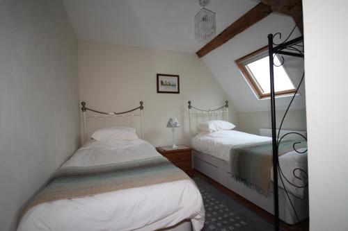 two beds in a small room with a window at Holiday home Le Pressoir in Domfront