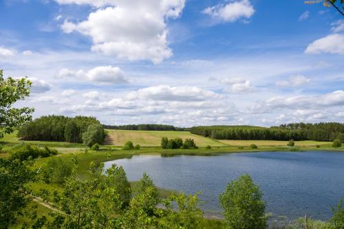 a large lake in a field with trees and clouds at Kaszubska Odskocznia Ostoja Bukowo in Borowy Młyn