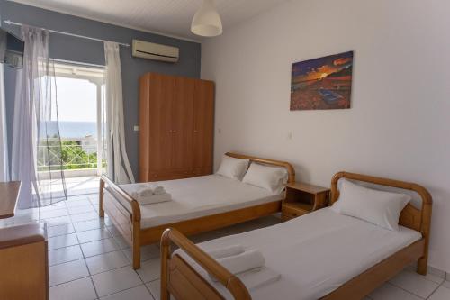 een kamer met 2 bedden en een raam met uitzicht op de oceaan bij Fuga Rooms in Kanali