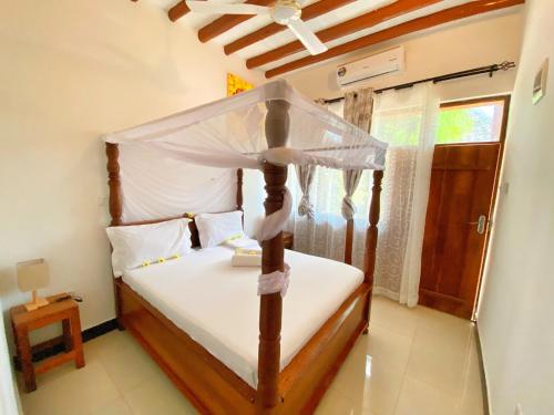 a bedroom with a canopy bed and a window at Utulivu Bungalow in Nungwi