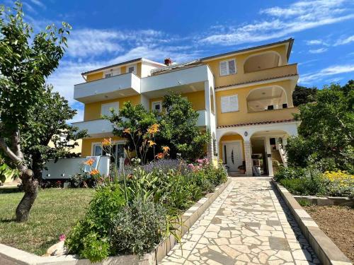 a yellow building with a garden in front of it at Haus Zdenka in Rab