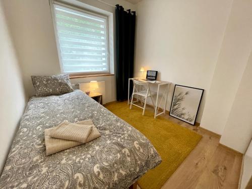 a bedroom with a bed and a window and a table at Apartament NOTI Gdynia z parkingiem in Gdynia