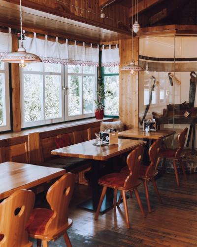 a restaurant with wooden tables and chairs and windows at Hotel Mölltalerhof in Rangersdorf
