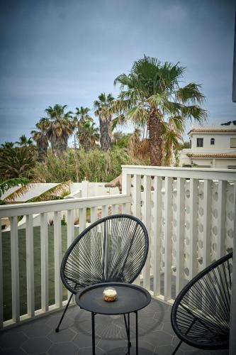 two chairs and a table on a balcony with palm trees at Labreña Hotel in Los Caños de Meca
