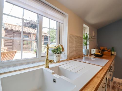 a kitchen with a large white sink and a window at Bluebird Cottage in Higham