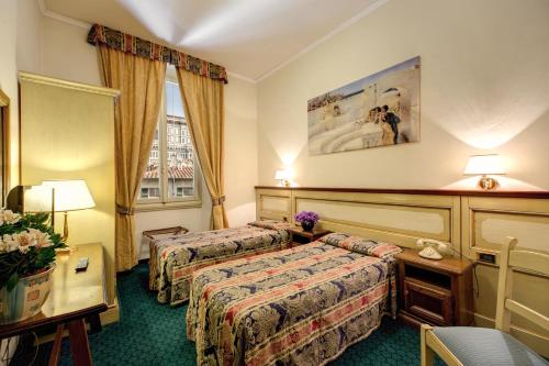 a hotel room with two beds and a table at Hotel De Lanzi in Florence