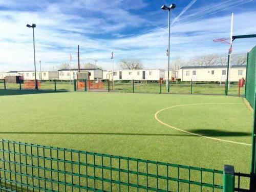 a tennis court with a net on a field at Lodge Sleeps 8- Parking Wifi Campsite Amenities in Jaywick Sands