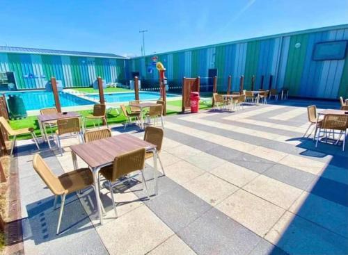 a patio with tables and chairs and a pool at Lodge Sleeps 8- Parking Wifi Campsite Amenities in Jaywick Sands