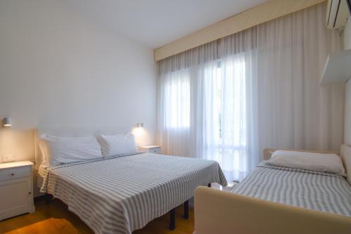 a bedroom with two beds and a window at Hotel Janeiro in Caorle