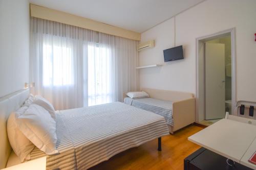 a small room with two beds and a window at Hotel Janeiro in Caorle