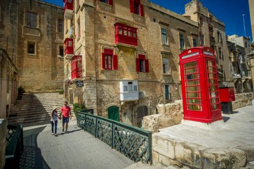a red phone booth and a woman walking in front of a building at Central Family Apartment in Valletta