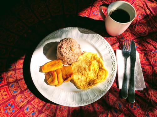 a plate of food with eggs and carrots and a cup of coffee at Casajungla Hostel in Jacó