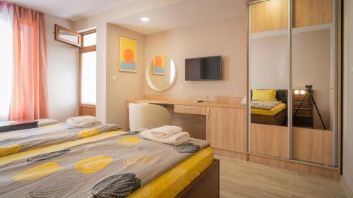 a room with two beds and a desk and a television at Guest House Karamihalevi in Sozopol