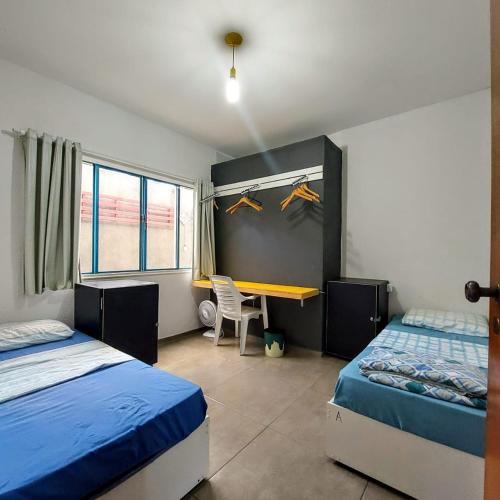 a bedroom with two beds and a desk in it at Hostel Brooklin in São Paulo