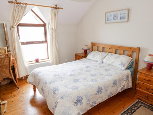 a bedroom with a bed with a blue and white comforter at King Cottage in Cleggan