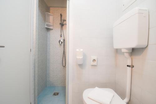 a white bathroom with a toilet and a shower at Hotel Janeiro in Caorle