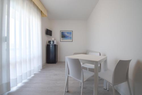 a dining room with a white table and chairs at Hotel Janeiro in Caorle