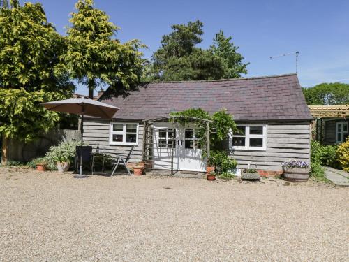 a white cottage with an umbrella and a gravel driveway at The Pottery in Urchfont
