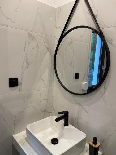 a white bathroom with a sink and a mirror at Przystań Leleszki in Leleszki
