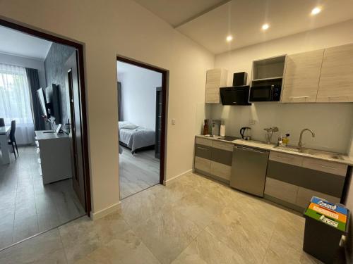 a kitchen with a sink and a room with a bed at Apartamenty "SZKIEŁKO" in Koszalin