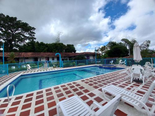 a swimming pool with white chairs and a table and chairs at Finca Hotel Villa Del Sol in Pueblo Tapao