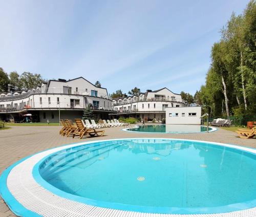 a large swimming pool in the middle of a resort at Pine Point Apartament with terrace, shared pool, tennis court in Pobierowo