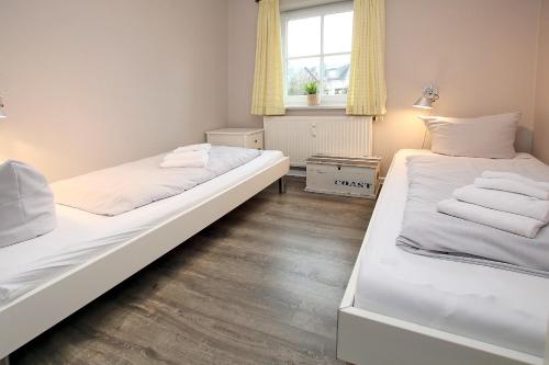 Duas camas num pequeno quarto com uma janela em Badestra_e 18 a_ Whg_ 4 em Wyk auf Föhr