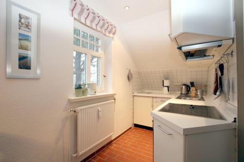 eine kleine Küche mit einem Waschbecken und einem Fenster in der Unterkunft Am Grünstreifen 31, Whg. 6 "Strandgut" in Wyk auf Föhr