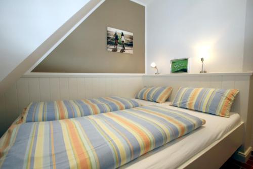 ein Bett mit gestreiften Kissen in einem Schlafzimmer in der Unterkunft Am Grünstreifen 31, Whg. 6 "Strandgut" in Wyk auf Föhr