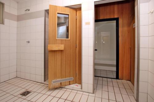 a bathroom with a wooden door and white tiles at Doerpstraat 9_ Whg_ 3 in Wyk auf Föhr