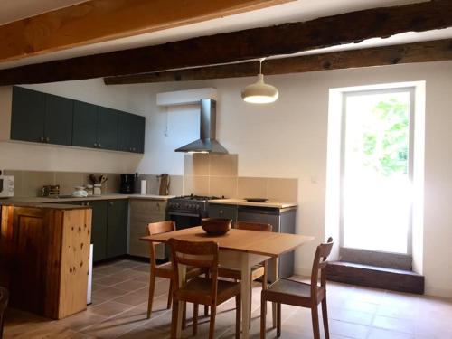 a kitchen with a wooden table and chairs and a kitchen with a window at Les pieds dans l'eau- gîte l'Estancot-plage privée in Blacons