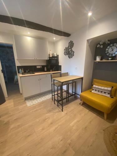 eine Küche mit einem Tisch und einer gelben Couch in einem Zimmer in der Unterkunft A l’ombre du géant de Provence in Mormoiron