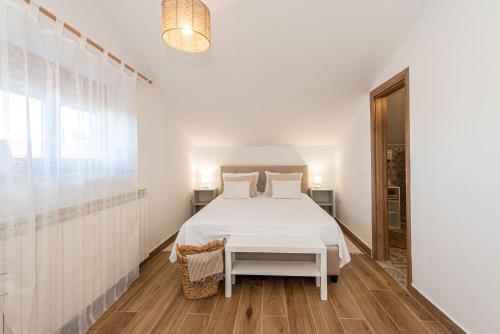a white bedroom with a bed and a table at Guest house DaLi in Rovinj