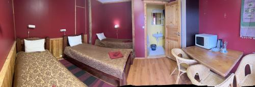 a room with two beds and a tv on a wall at Hotel Repvåg in Repvåg