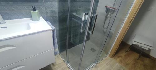 une douche avec une porte en verre à côté d'un lavabo dans l'établissement Piso centrico y tranquilo, à Vigo