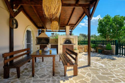 an outdoor patio with a table and a fireplace at Chrisi`s house with jacuzzi in Moírai