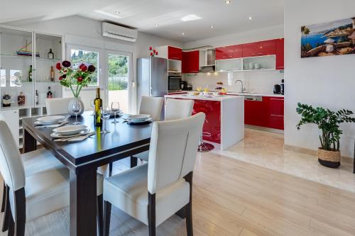 a kitchen with red cabinets and a dining table and chairs at Apartman ViEw in Preko