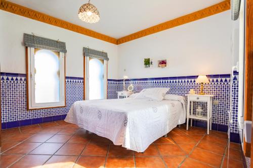 1 dormitorio azul y blanco con 1 cama y 2 ventanas en Ático El Pasero con Solarium y Barbacoa, en Alcaucín