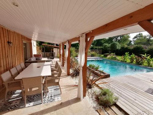 un patio avec une table et des chaises et une piscine dans l'établissement Magnifique villa avec piscine, à Sainte-Eulalie-en-Born