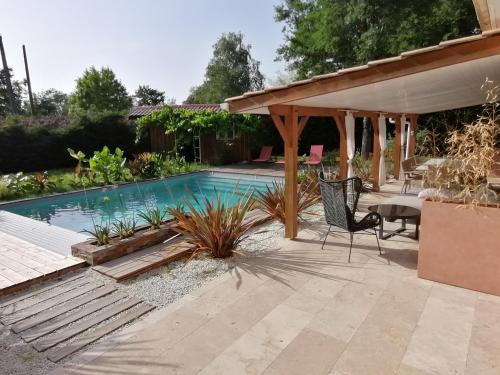 - une piscine dans un jardin avec une pergola dans l'établissement Magnifique villa avec piscine, à Sainte-Eulalie-en-Born