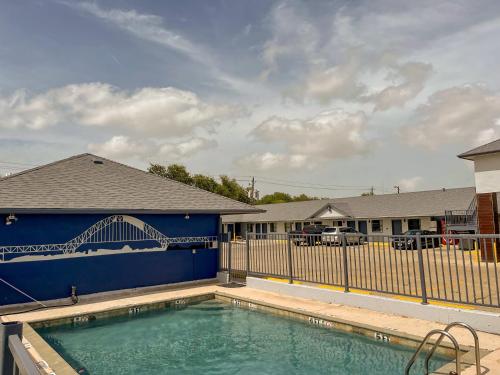 une piscine avec une clôture bleue et un pont dans l'établissement Deluxe Inn & Suites, à Corpus Christi